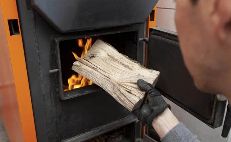 Homme met du bois de chauffage dans son poêle à bois